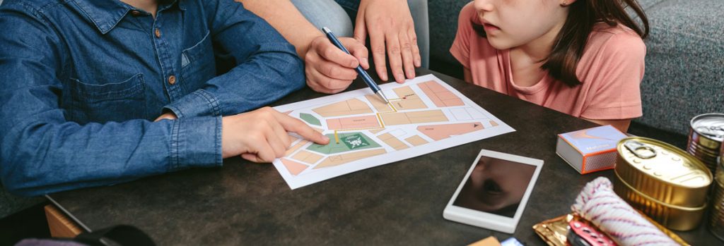 Mother explaining to her children the assembly point map while preparing emergency backpacks