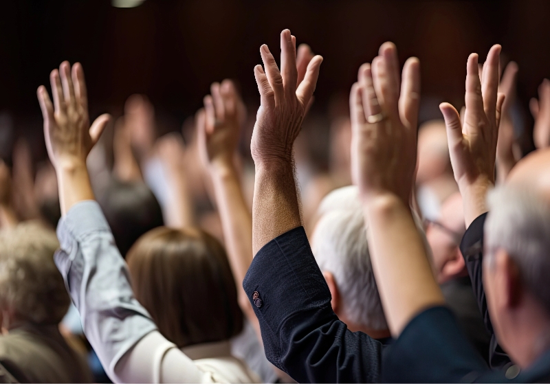 a diverse audience raises their hands